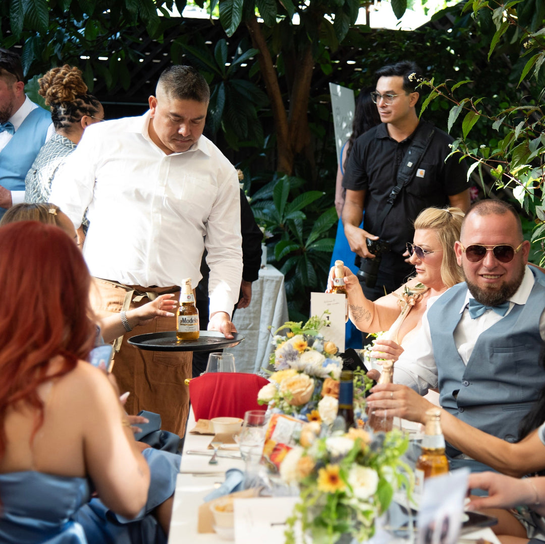 Group of people sitting at a table outdoors with greenery in the background