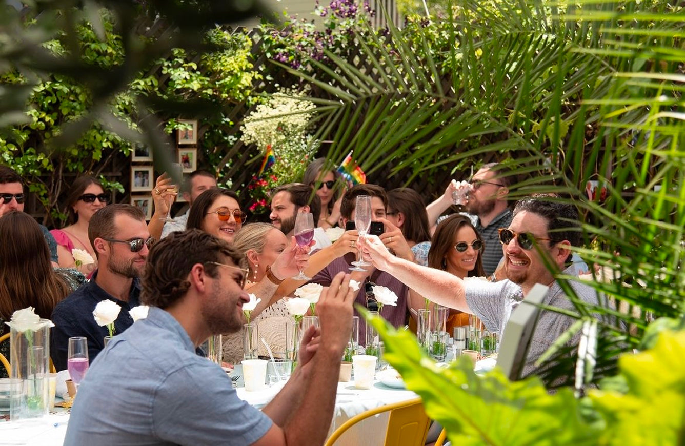 Group of people at an outdoor event with greenery and floral decorations.