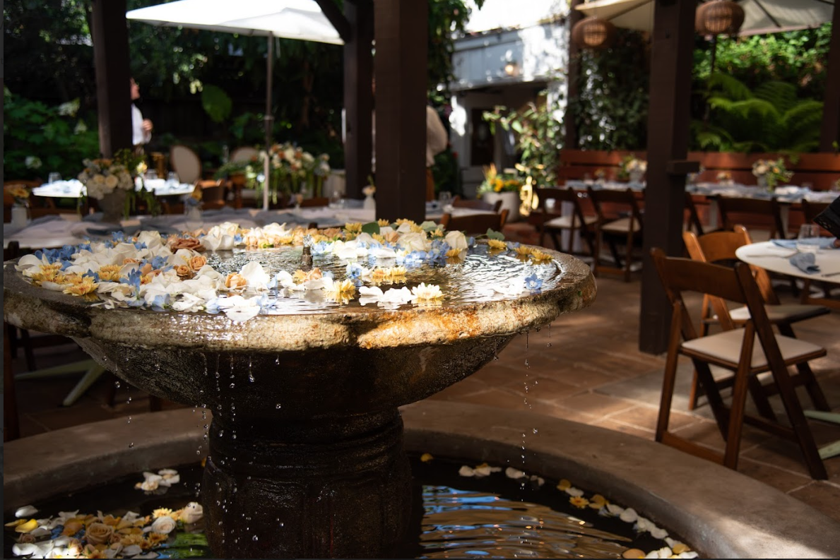 Fountain with decorative stones in an outdoor setting with tables and chairs.