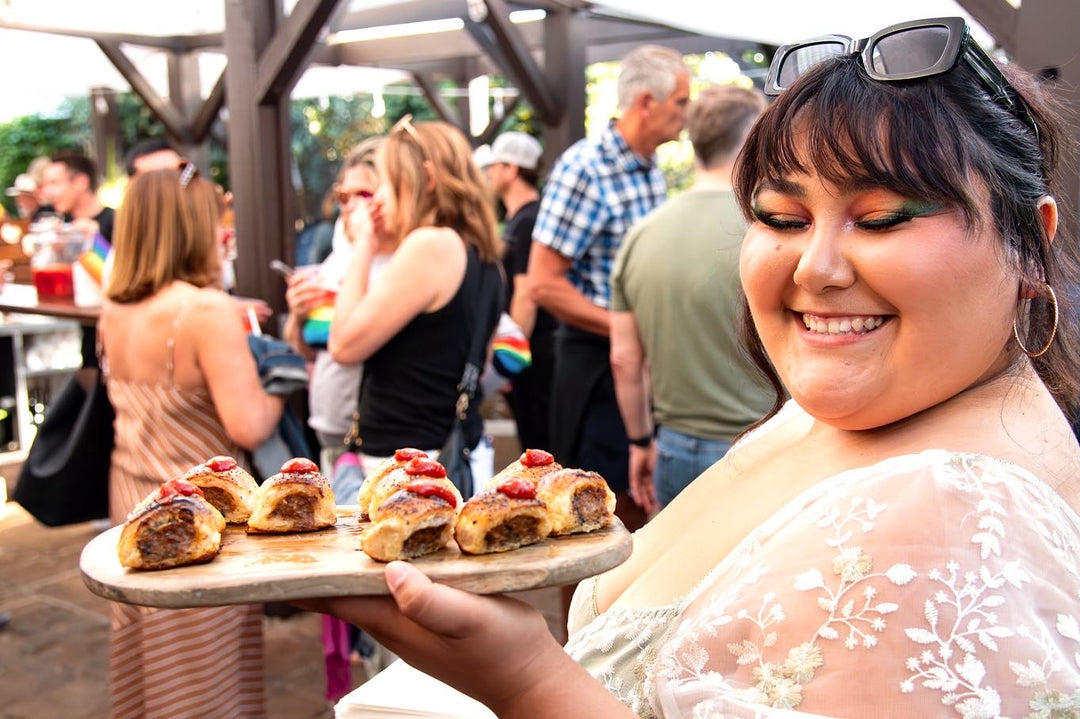 Woman holding a tray of food at an outdoor event with people in the background