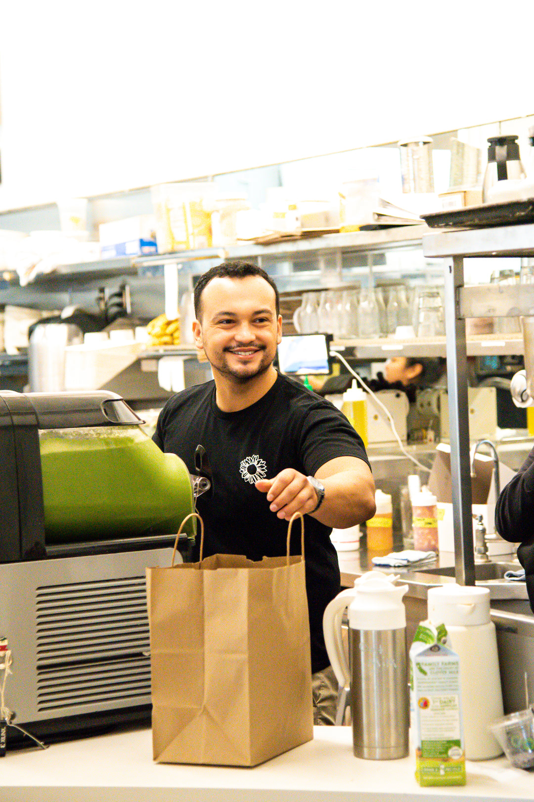 Person in a kitchen holding a brown paper bag