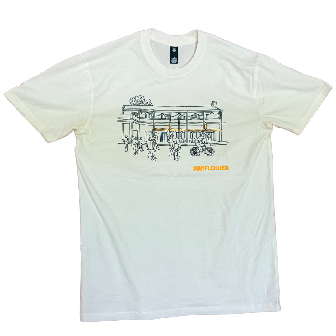 Printed on a soft, natural 100% cotton, this piece features an illustrated view of our space—where slow mornings turn into sunny afternoons.

Easy to wear, easy to love, and made to be part of your everyday.