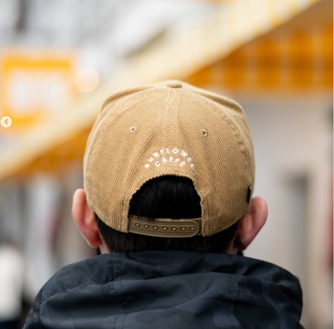 A soft corduroy cap embroidered with Waffles — golden, nostalgic, and always a good idea.

Golden mornings deserve a golden hat.

This corduroy cap features Waffles embroidered on the front with Sunflower Caffé stitched on the back — a playful nod to one of our most-loved brunch classics. Designed for easy mornings, cozy layers, and those who know breakfast is best enjoyed slow.

Finished with an adjustable snapback for everyday comfort.

Soft corduroy fabric
Embroidered Waffles front detail
“Sunflower Caff