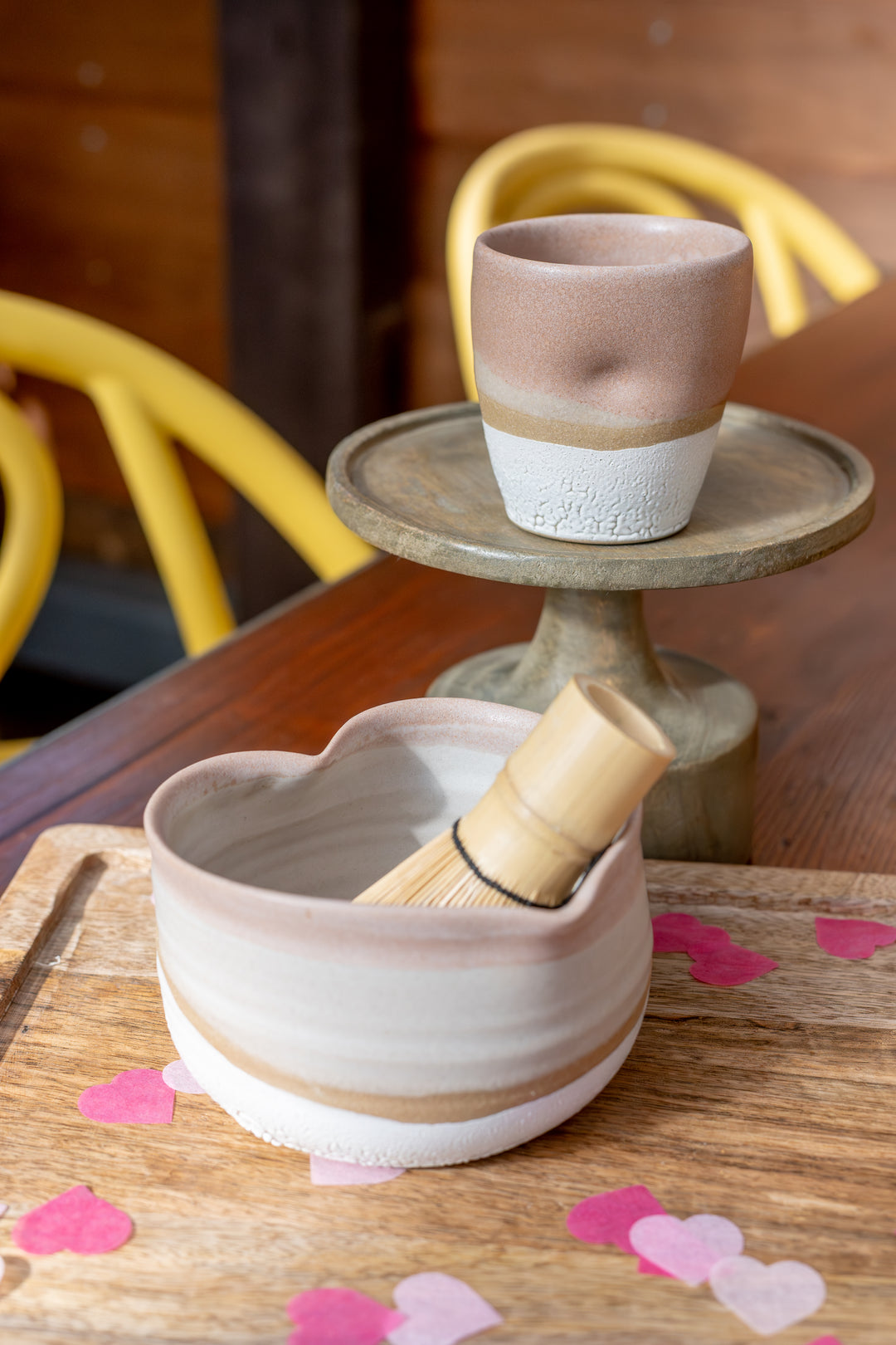 Ceramic bowl with a whisk on a wooden surface with heart-shaped confetti.