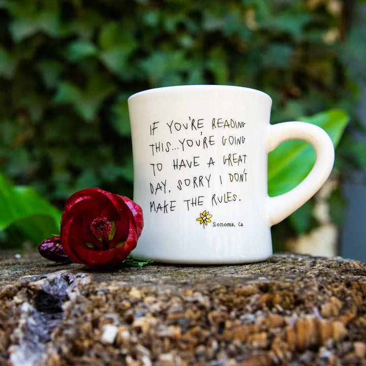 White coffee mug with the text "if you're reading this...you're going to have a great day, sorry I don't make the rules"