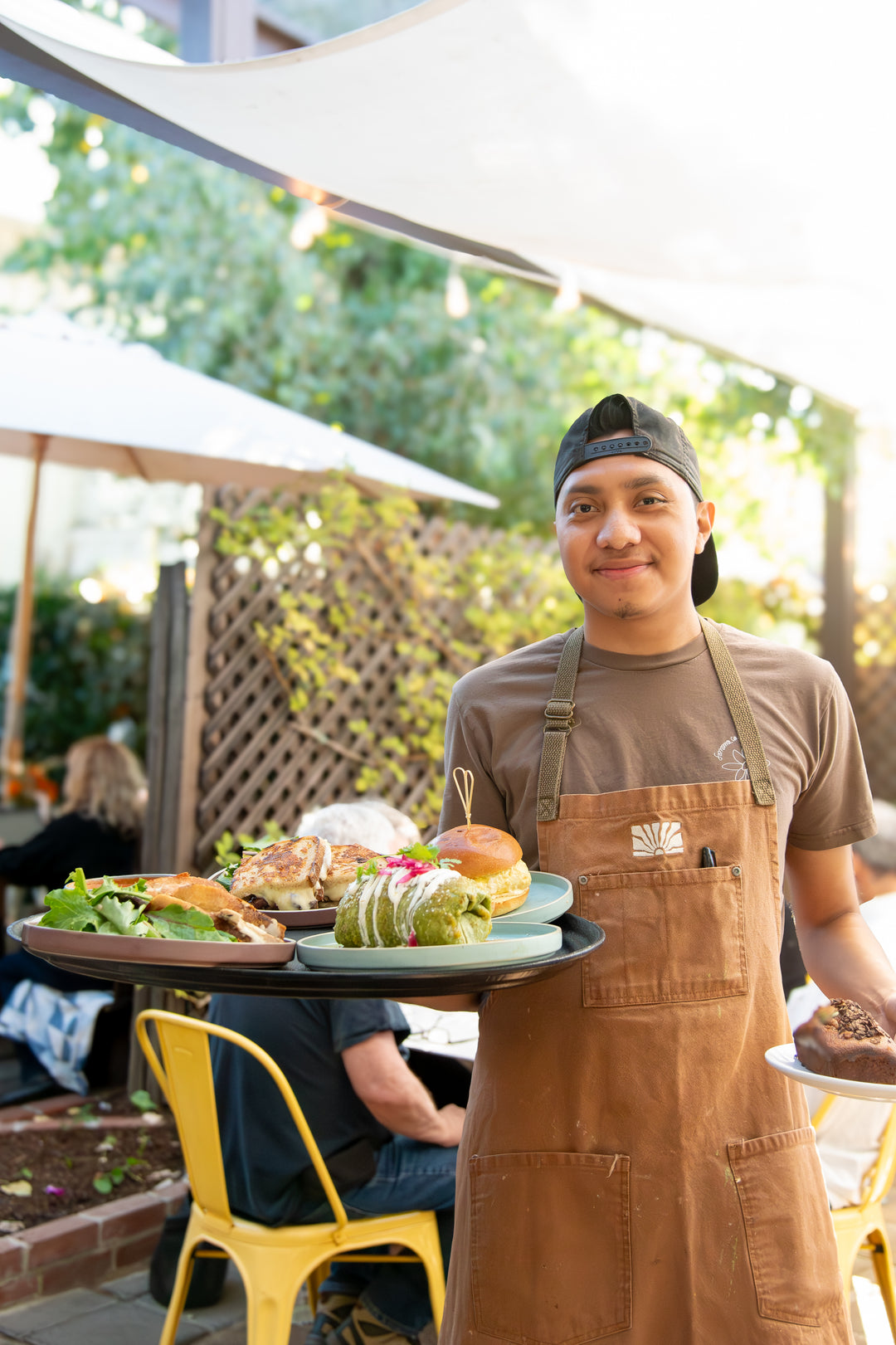Person wearing an apron holding a tray of food outdoors