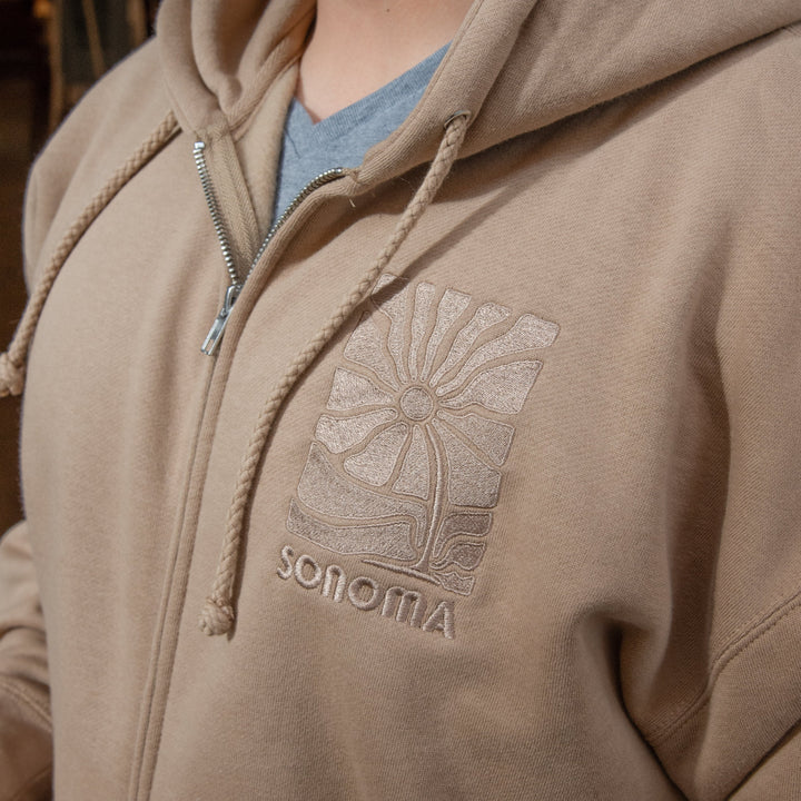 Introducing the "Groovy Sonoma" Heavyweight Zip Hooded Sweatshirt, which is expertly crafted using high-quality heavyweight material in a stylish Sandstone shade. We have used premium spun cotton to create a velvety and robust base, making you feel like you're wrapped in a cozy blanket. The sweatshirt features a comfortable hood with a fleece lining, durable round drawstring, nickel eyelets, a nickel zipper, and 1x1 ribbing at the cuffs and waistband for a perfect fit. 